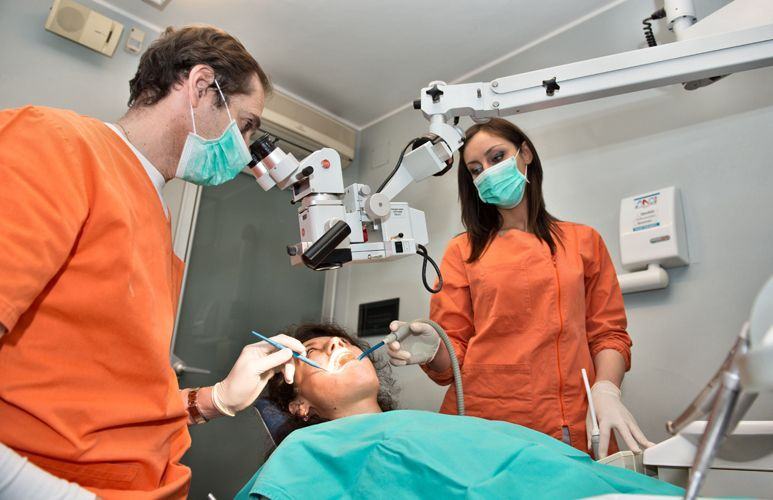 Un odontoiatra e un'assistente al microscopio operatorio