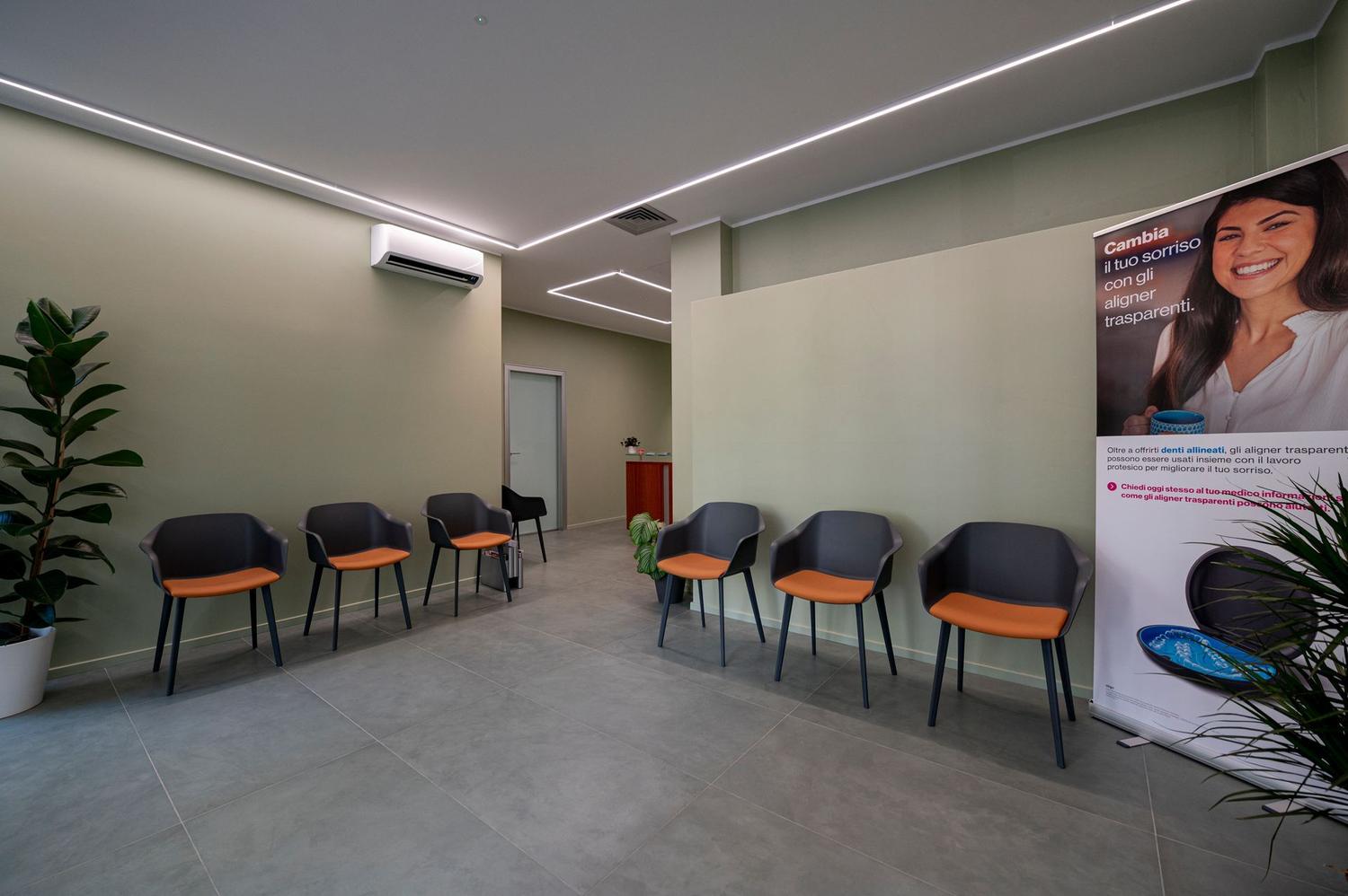 La sala d'attesa dello studio, con poltroncine e parete verde salvia
